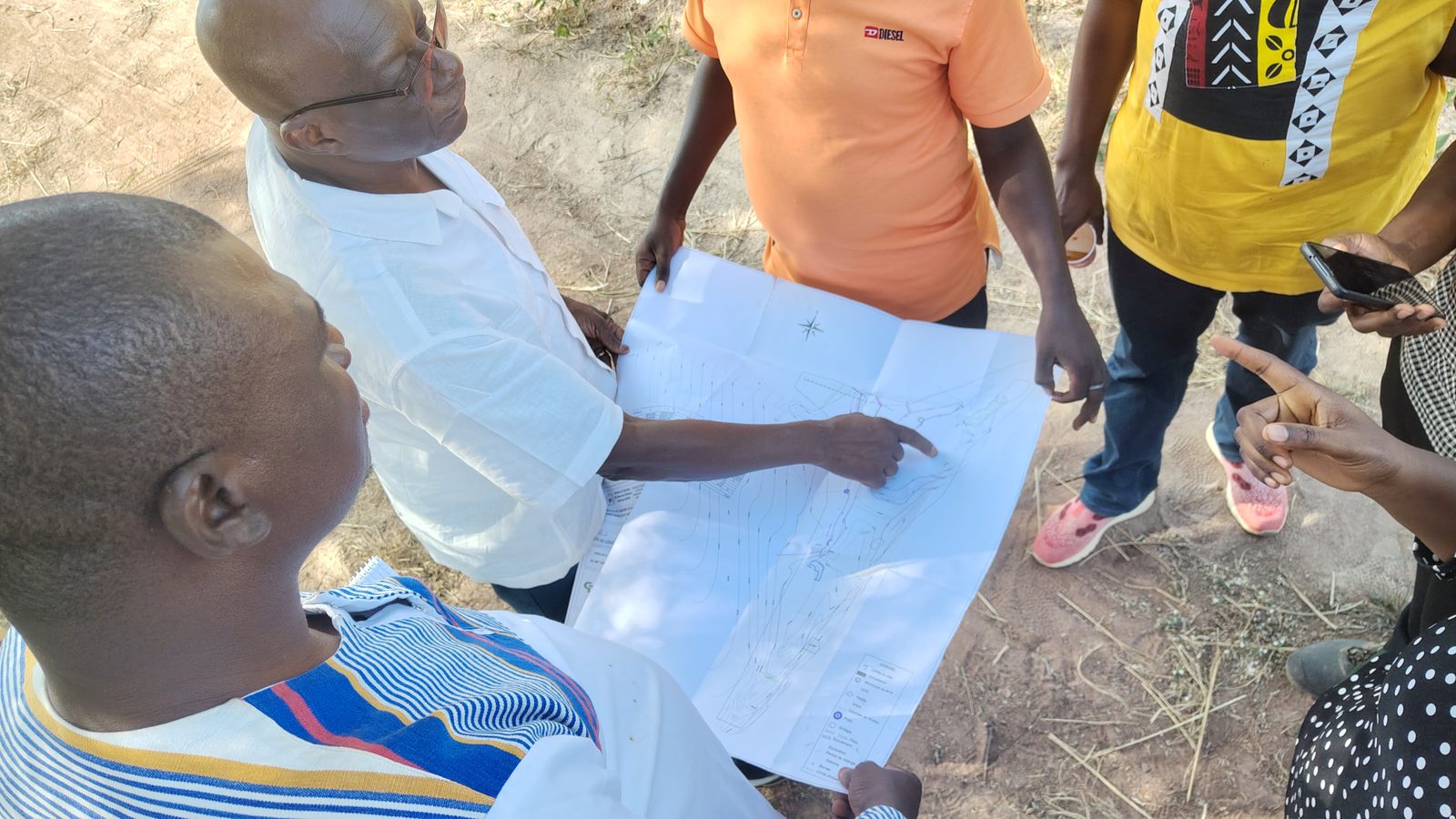Équipe projet examinant un plan d’aménagement de bas-fond sur le terrain